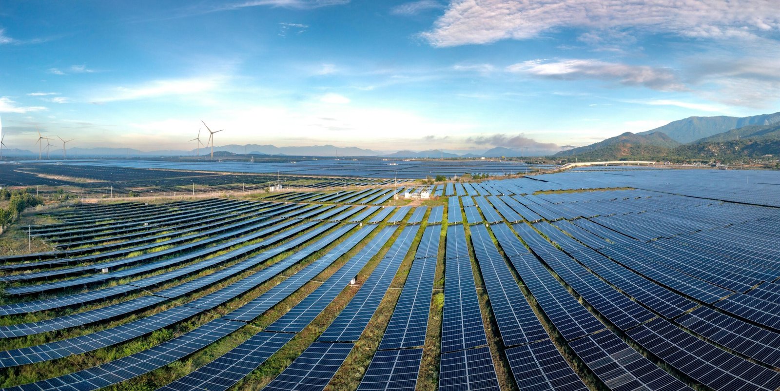 Expansive solar farm and wind turbines harnessing renewable energy at sunrise, showcasing sustainable technology.